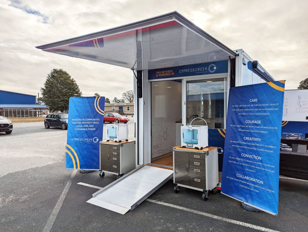 A mobile classroom sits in a parking lot with the door open